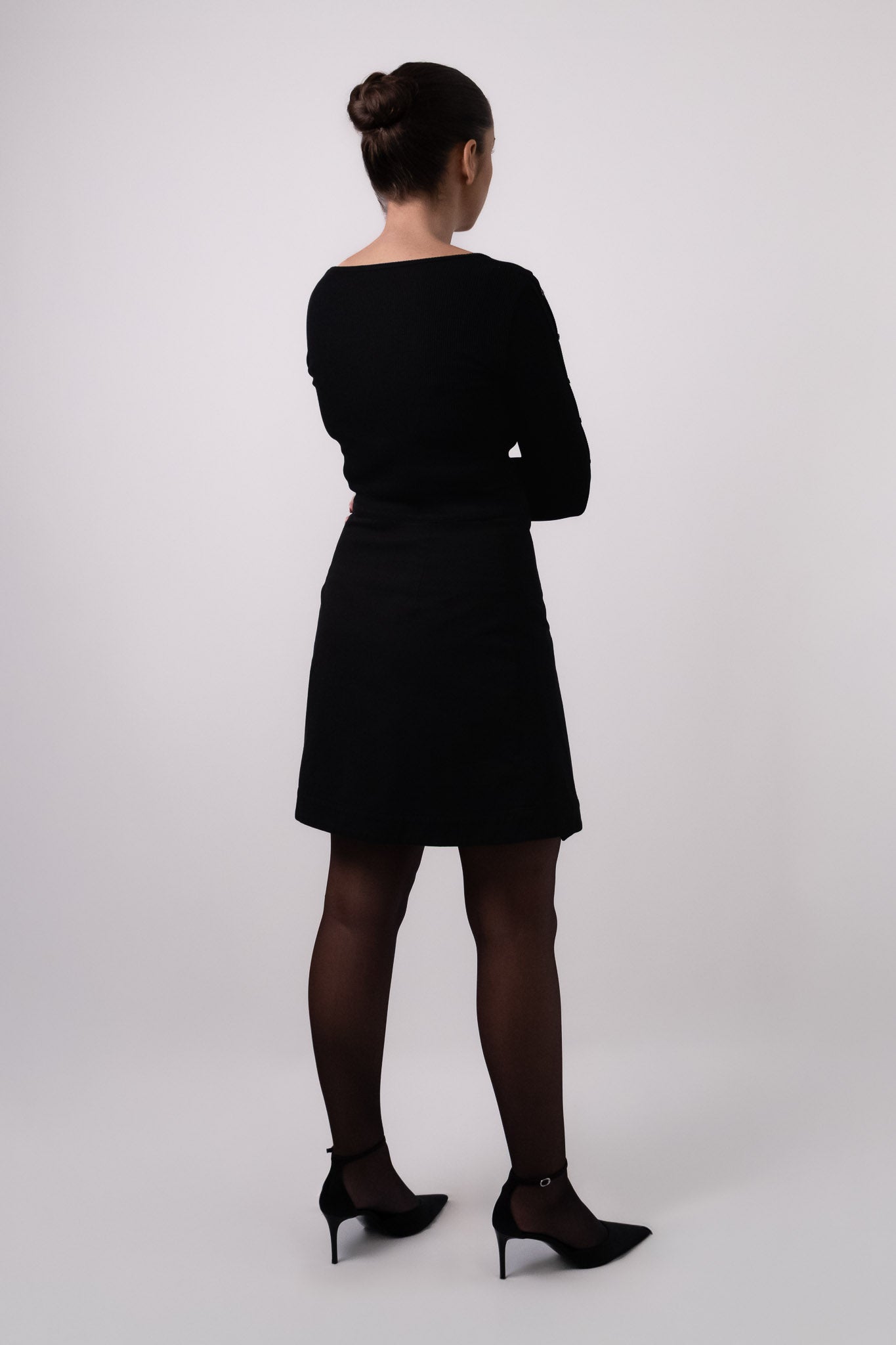 Jupe noire portefeuille MIA portée avec le Top manches longues SOHO de dos. DILAA