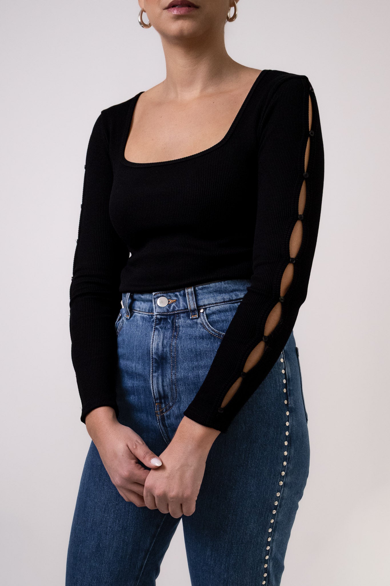 Top noir Soho en maille côtelée, col carré, avec détails découpés et boutonnés le long des manches, porté avec jean Pat taille haute. Marque DILAA