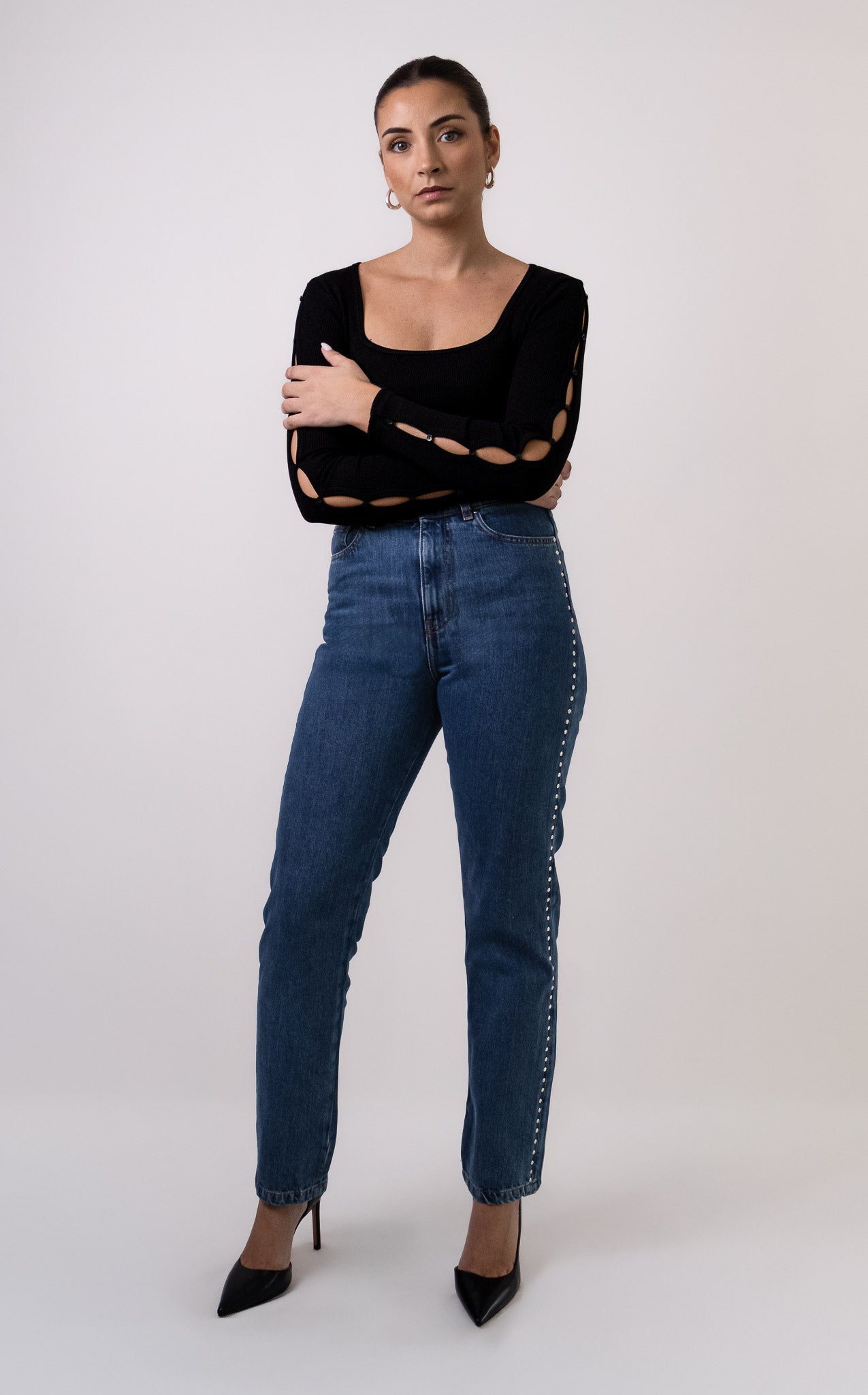 Top noir Soho en maille côtelée, col carré, avec détails découpés et boutonnés le long des manches, porté avec jean Pat taille haute. Vue de face. Marque DILAA