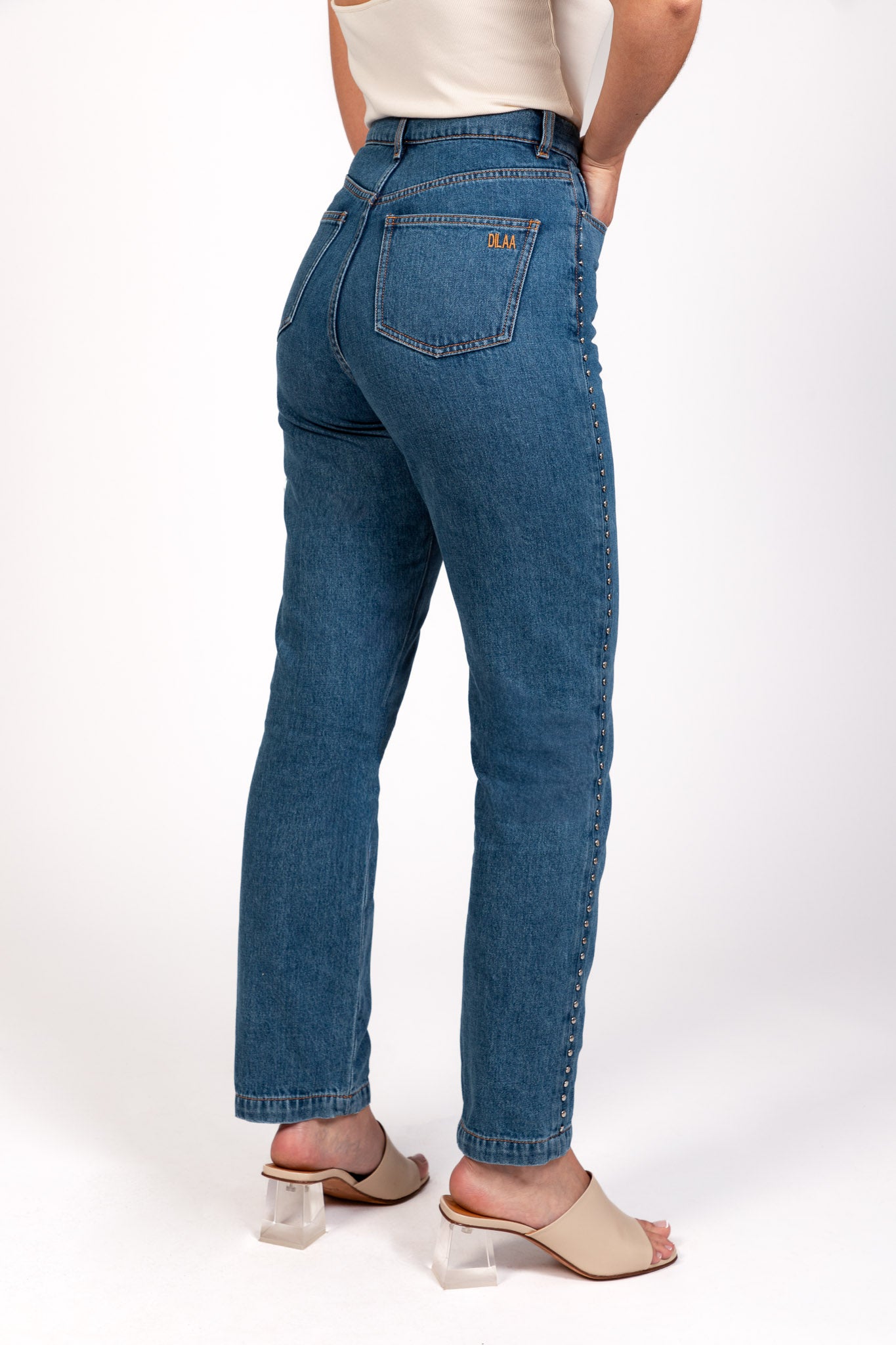 Jean Pat coupe droite avec détails cloutés sur les côtés, broderie DILAA sur la poche arrière, vue de dos. 