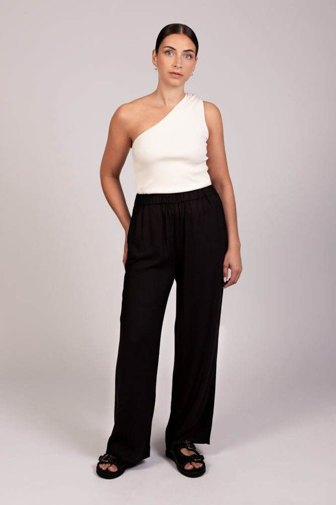 Pantalon noir fluide taille élastique MILO, coupe droite confortable, porté avec le top NOVA asymétrique écru - collection été DILAA