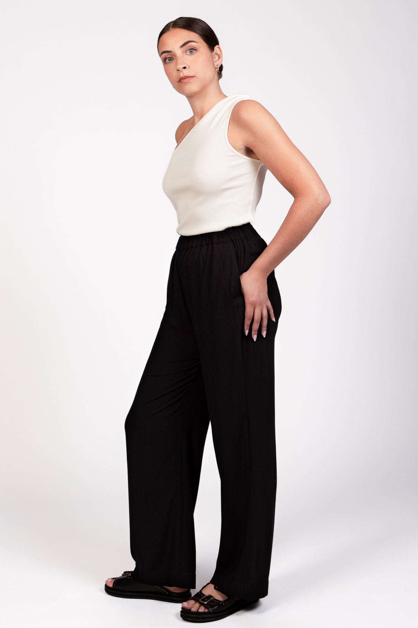 Pantalon noir fluide taille élastique MILO, coupe droite confortable, porté avec le top NOVA asymétrique écru - collection DILAA