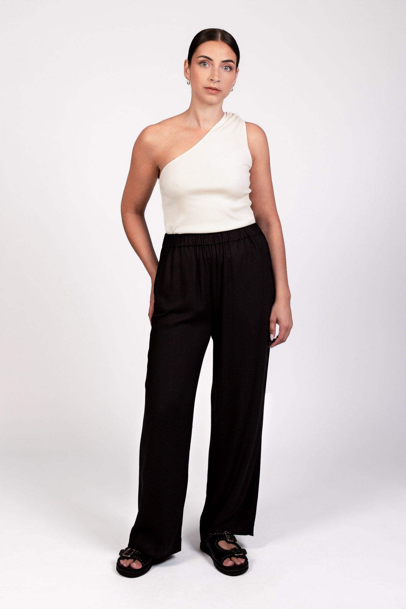 Pantalon noir fluide taille élastique MILO, coupe droite confortable, porté avec le top NOVA asymétrique écru - collection DILAA
