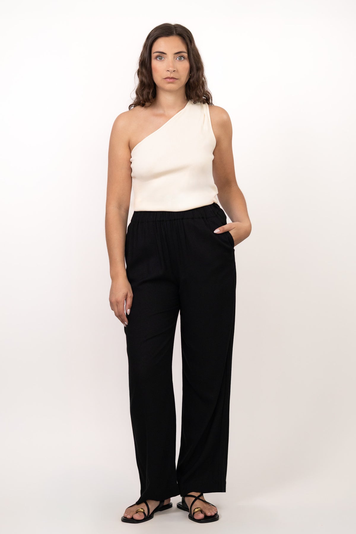 Pantalon noir fluide taille élastique MILO, coupe droite confortable, porté avec le top NOVA asymétrique écru - collection DILAA