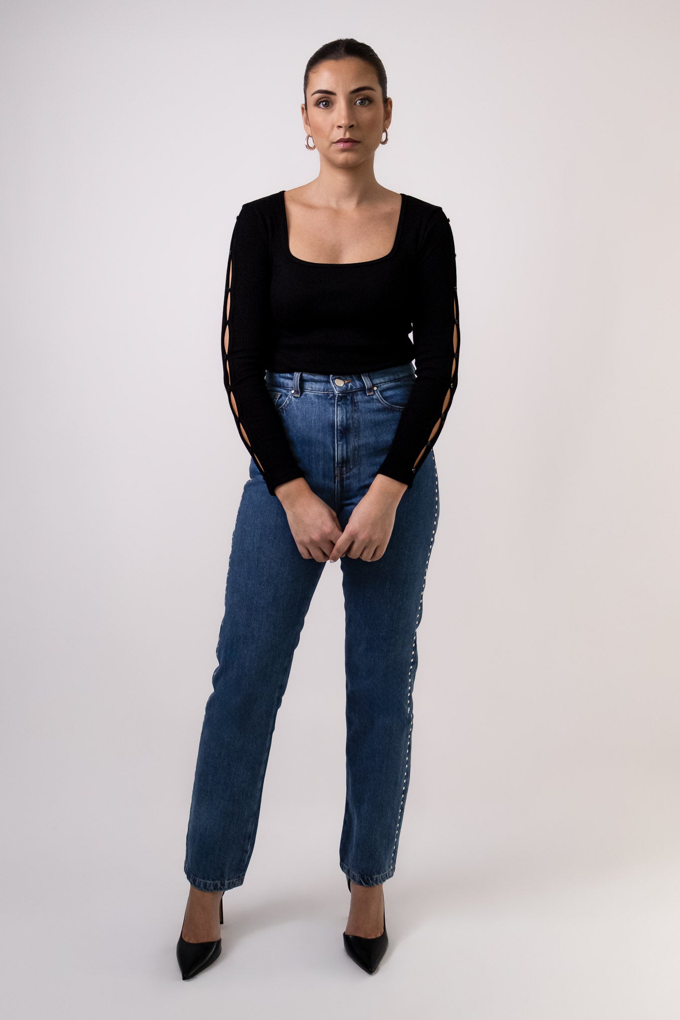 Top noir Soho en maille côtelée, col carré, avec détails découpés et boutonnés le long des manches, porté avec jean Pat taille haute. Marque DILAA